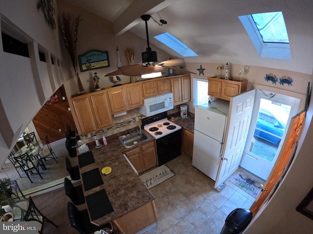 kitchen with ceiling fan, vaulted ceiling with skylight, sink, and white appliances