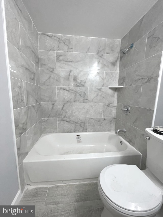 bathroom with tiled shower / bath combo and toilet