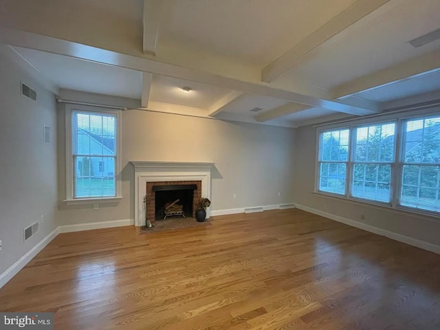 unfurnished living room featuring coffered ceiling, a healthy amount of sunlight, wood-type flooring, and beamed ceiling