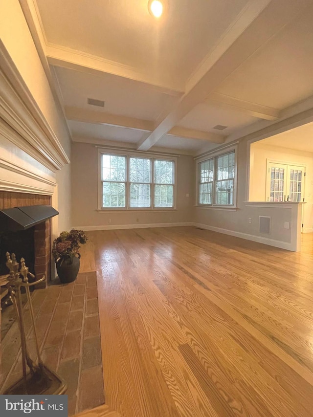 unfurnished living room with a brick fireplace, hardwood / wood-style floors, and beamed ceiling