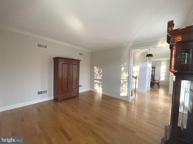 unfurnished living room featuring hardwood / wood-style floors and crown molding