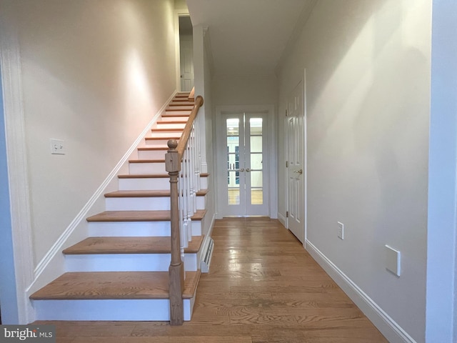 stairway with french doors and wood-type flooring