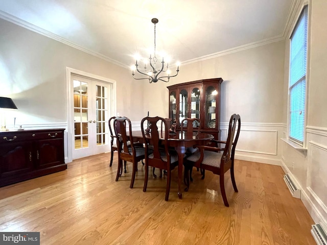 dining room with french doors, light wood-type flooring, crown molding, and a chandelier