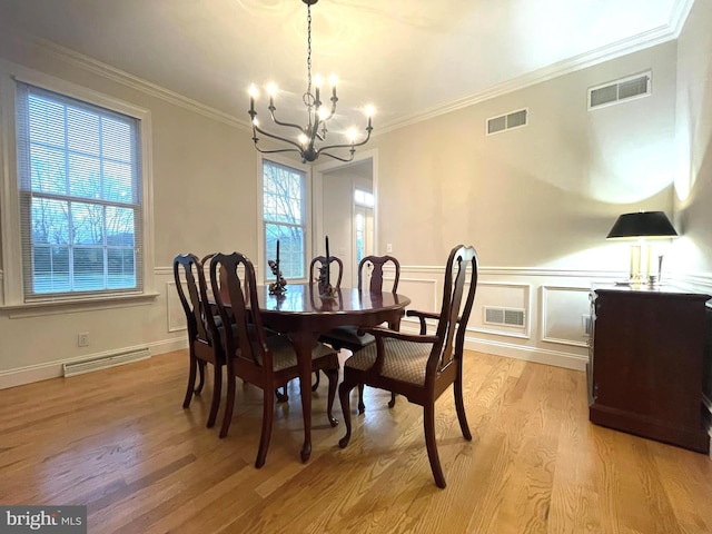 dining area featuring crown molding, a chandelier, and light hardwood / wood-style flooring