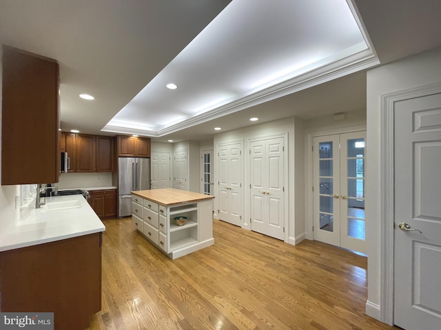 kitchen featuring light hardwood / wood-style floors, a kitchen island, wood counters, appliances with stainless steel finishes, and sink