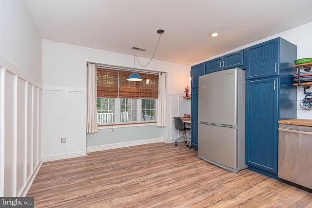 kitchen featuring blue cabinetry, pendant lighting, stainless steel appliances, and light hardwood / wood-style floors