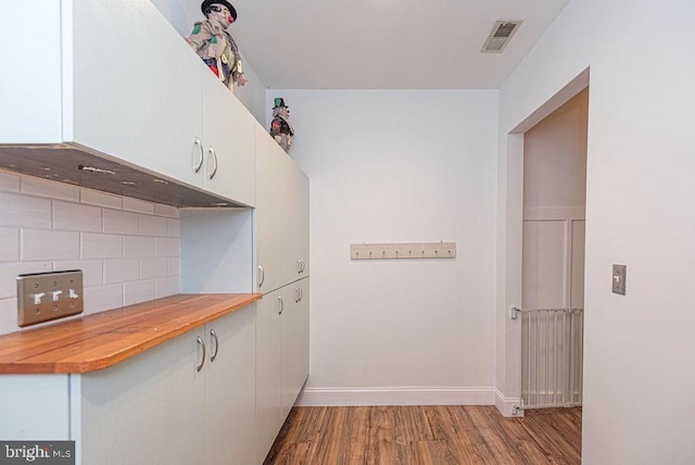 kitchen featuring hardwood / wood-style floors, white cabinets, wood counters, and tasteful backsplash