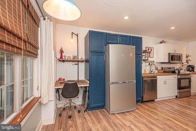 kitchen featuring blue cabinets, white cabinets, light hardwood / wood-style flooring, and stainless steel appliances