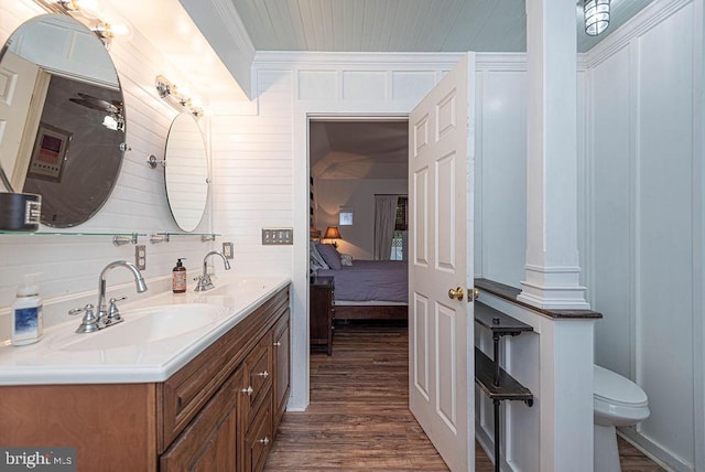 bathroom featuring hardwood / wood-style flooring, toilet, vanity, crown molding, and wooden walls