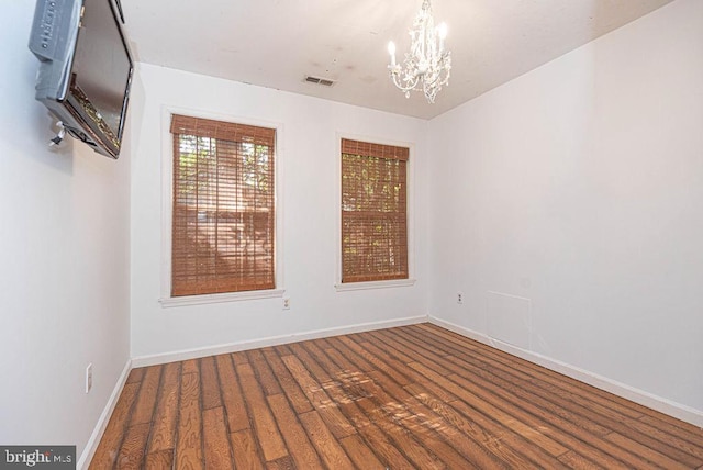 empty room featuring hardwood / wood-style floors and an inviting chandelier