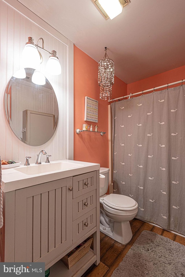 bathroom with hardwood / wood-style flooring, toilet, vanity, a chandelier, and walk in shower