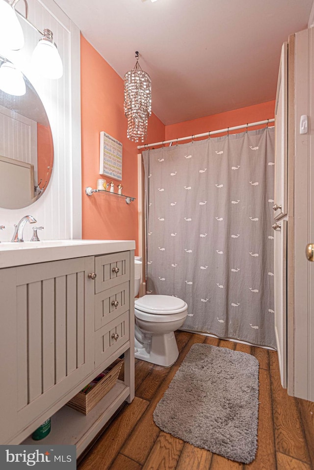 bathroom with toilet, a shower with curtain, hardwood / wood-style floors, a notable chandelier, and vanity