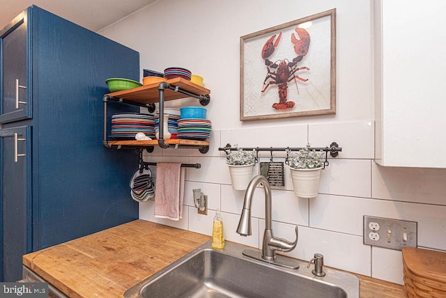 interior space with tasteful backsplash, blue cabinets, and sink