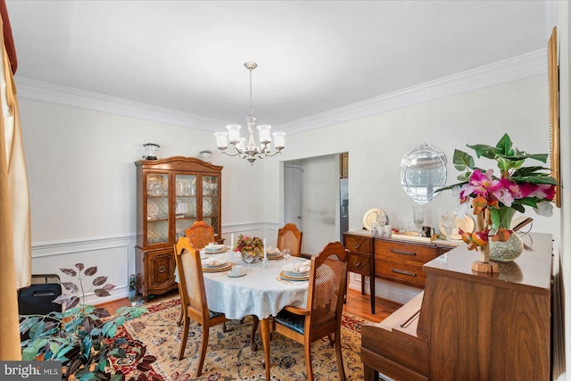 dining area featuring light hardwood / wood-style floors, crown molding, and a chandelier