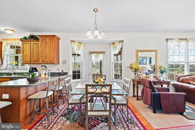 dining area with sink, a notable chandelier, and light hardwood / wood-style flooring