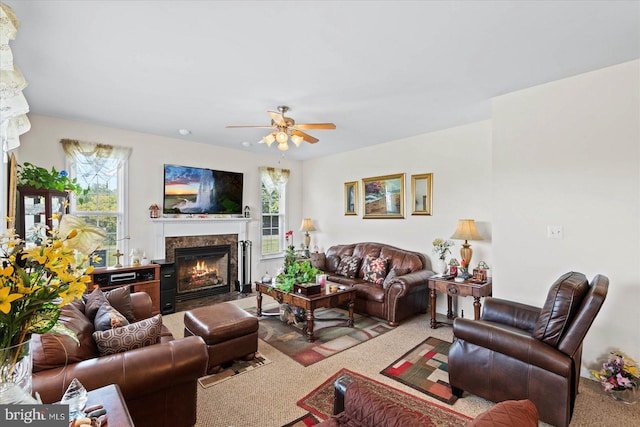 living room with a high end fireplace, carpet floors, and ceiling fan