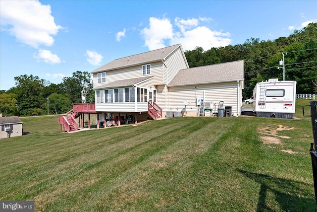 rear view of property with a yard, a sunroom, and a deck