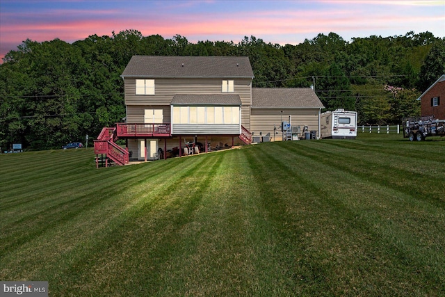 back house at dusk with a deck and a lawn