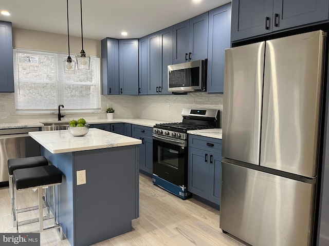 kitchen with light stone counters, a kitchen island, appliances with stainless steel finishes, light hardwood / wood-style floors, and a breakfast bar