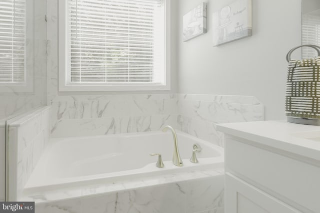 bathroom with tiled bath and vanity