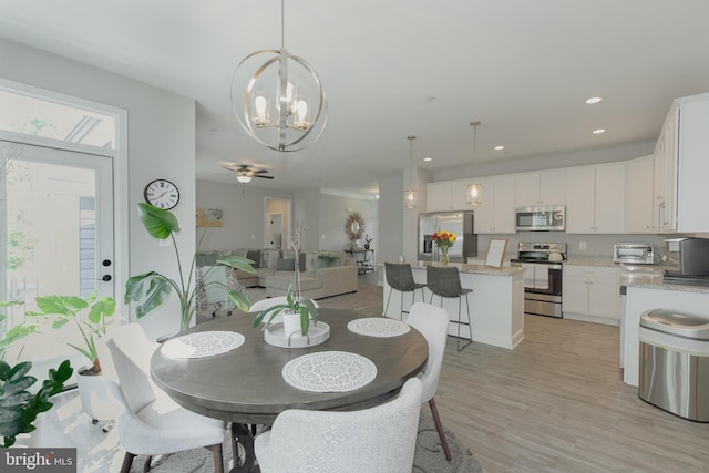 dining area featuring ceiling fan with notable chandelier and light hardwood / wood-style flooring