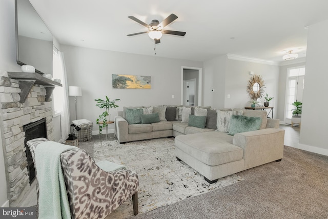 living room featuring carpet floors, a stone fireplace, and ceiling fan