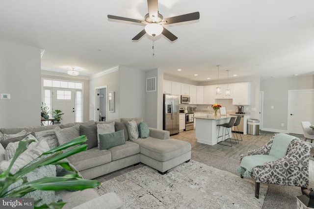 living room with crown molding, light hardwood / wood-style flooring, and ceiling fan