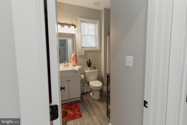 bathroom with hardwood / wood-style flooring, vanity, and toilet