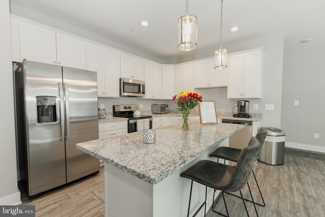 kitchen featuring light hardwood / wood-style floors, pendant lighting, white cabinets, appliances with stainless steel finishes, and a center island