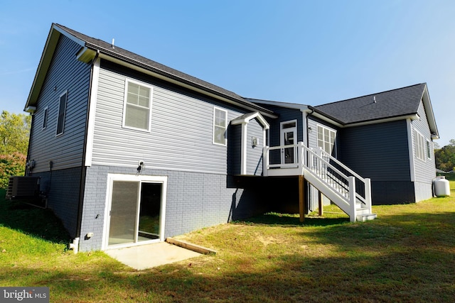 rear view of house featuring a lawn and central AC