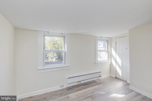 empty room featuring light wood-type flooring and a baseboard radiator