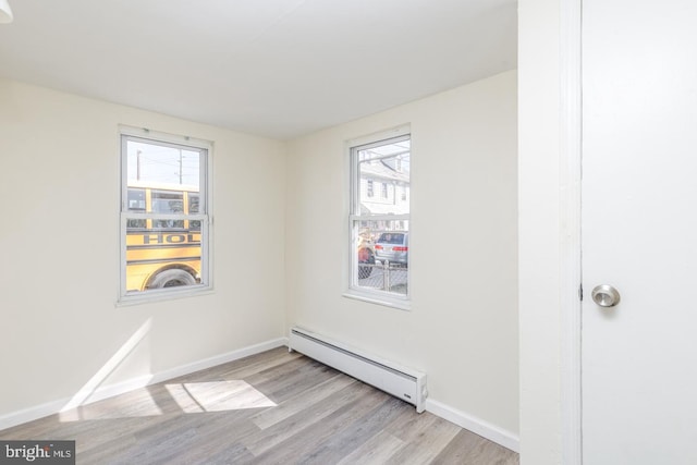 spare room with plenty of natural light, a baseboard radiator, and light wood-type flooring