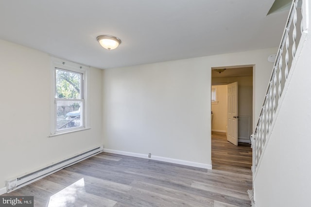 empty room featuring hardwood / wood-style floors and a baseboard heating unit