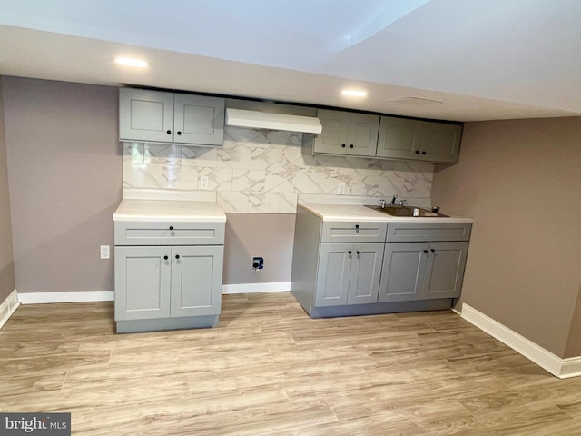 kitchen featuring decorative backsplash, light wood-type flooring, and gray cabinets