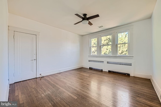 empty room featuring radiator heating unit, ceiling fan, and dark hardwood / wood-style flooring