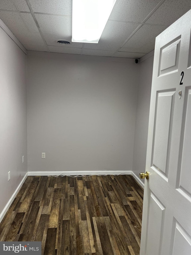 spare room with a paneled ceiling and dark wood-type flooring