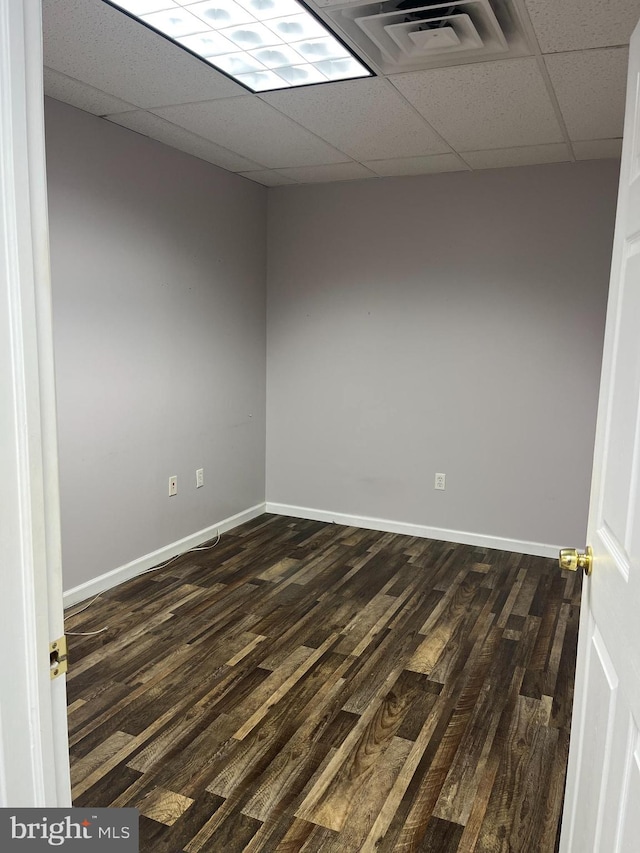 empty room featuring a paneled ceiling and dark wood-type flooring