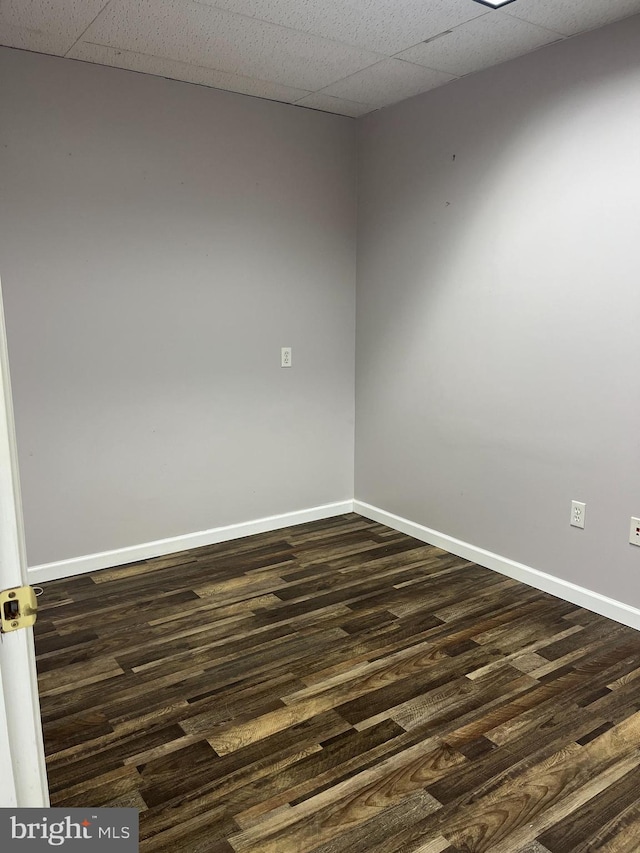 empty room with a paneled ceiling and dark wood-type flooring