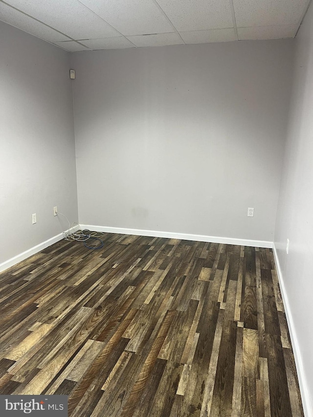 spare room featuring a paneled ceiling and dark hardwood / wood-style flooring