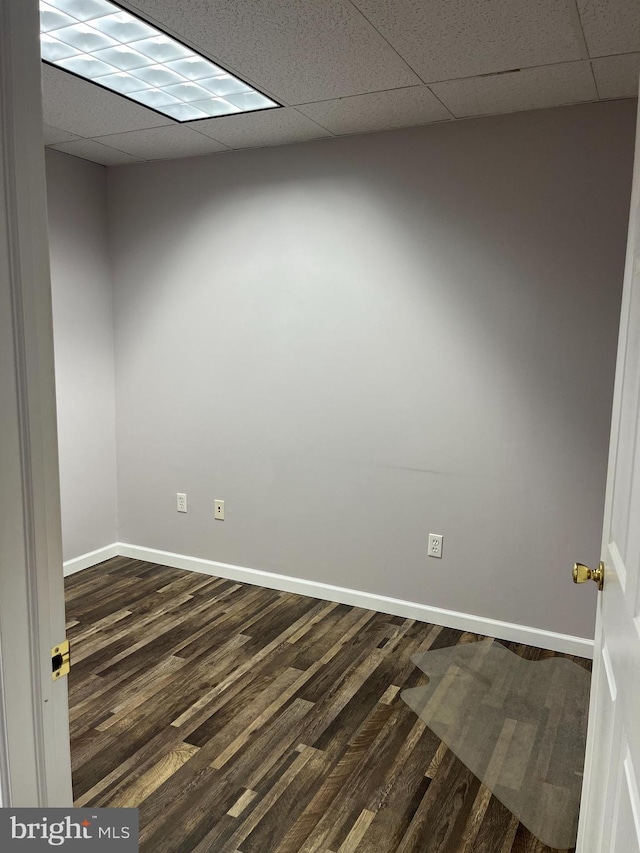 unfurnished room featuring a paneled ceiling and dark hardwood / wood-style flooring