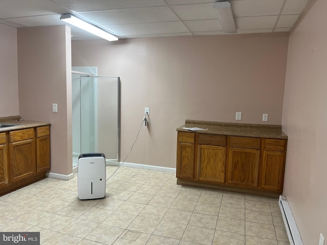 bathroom featuring a drop ceiling, a baseboard heating unit, a shower with shower door, and vanity