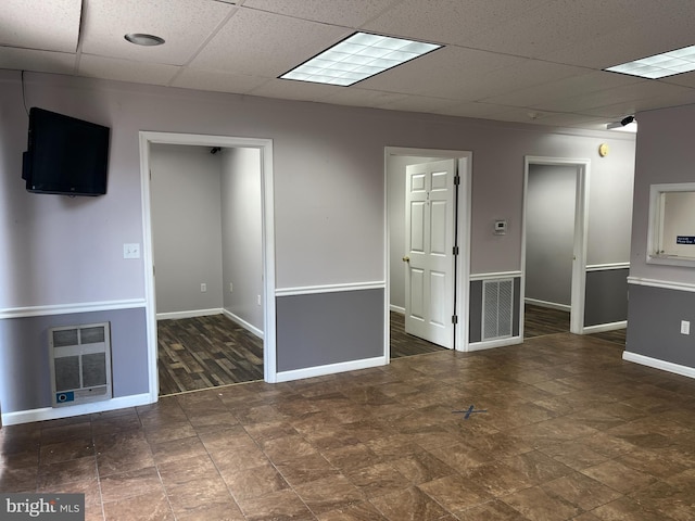 empty room featuring a drop ceiling and heating unit