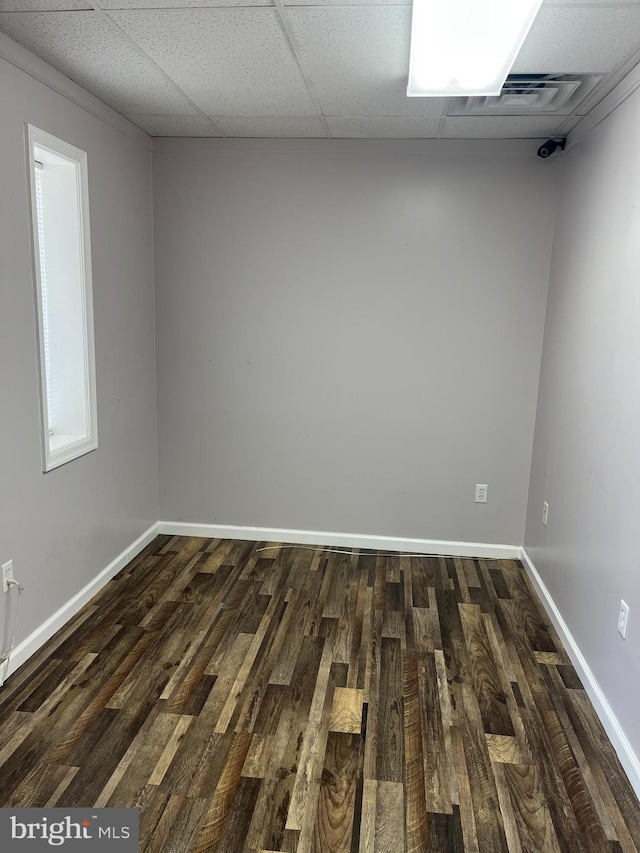 empty room with a paneled ceiling and dark wood-type flooring