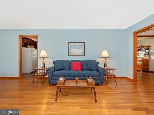 living area with light wood-type flooring and baseboards