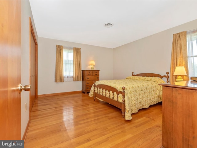 bedroom featuring light wood finished floors, visible vents, and baseboards