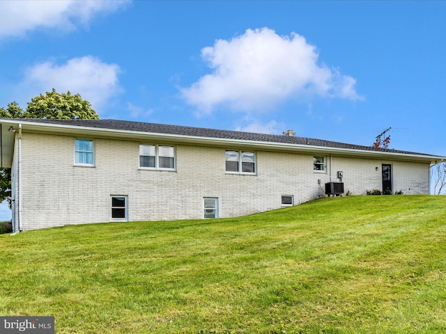 back of property featuring cooling unit and a lawn