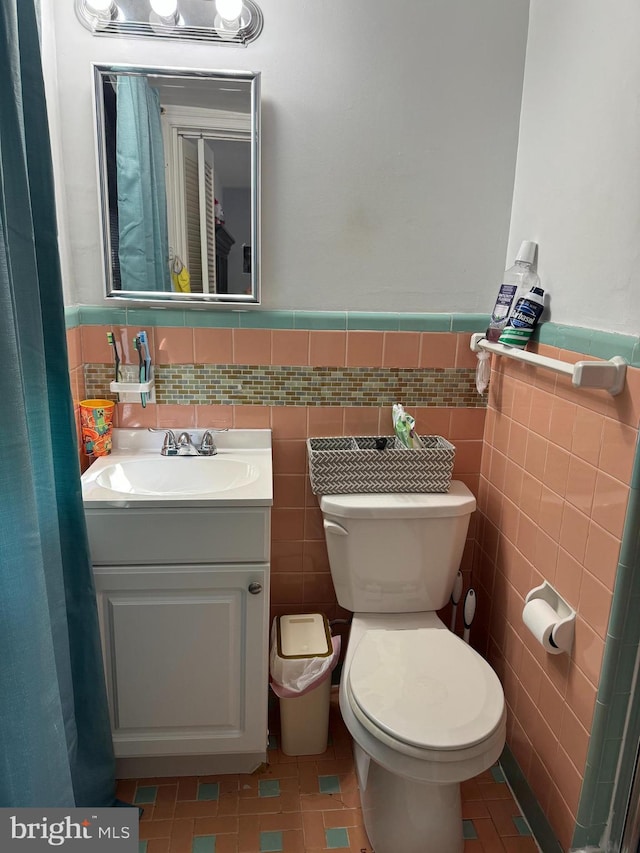 bathroom with tile walls, vanity, and toilet