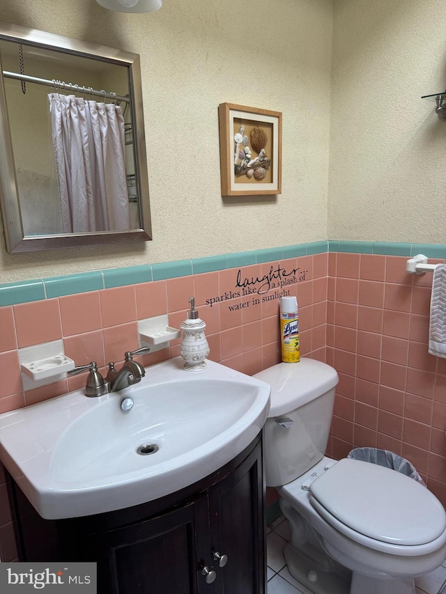 bathroom with vanity, a shower with curtain, toilet, and tile walls