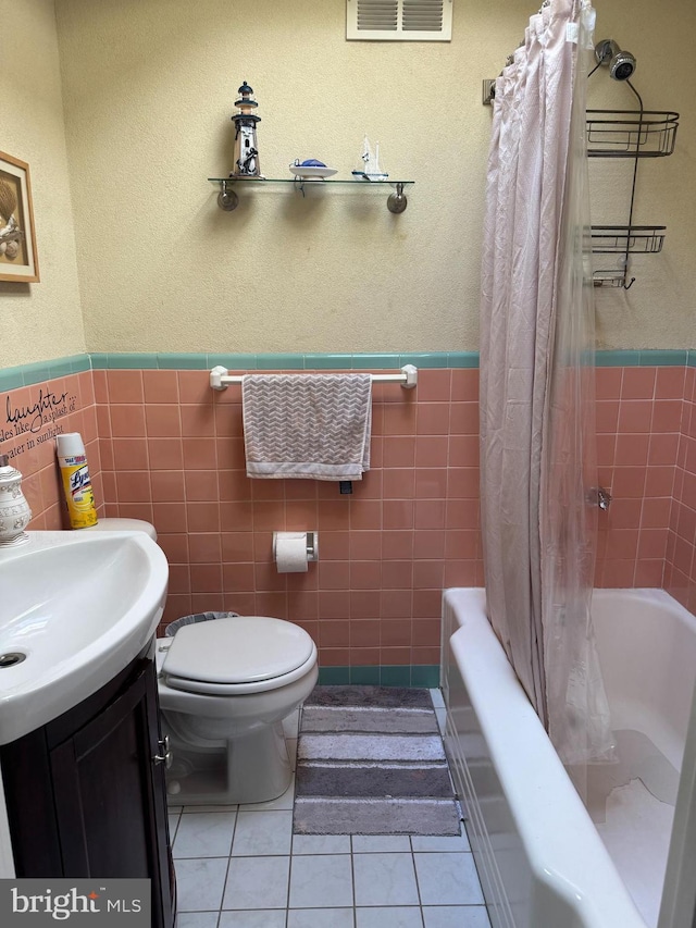 full bathroom featuring toilet, vanity, tile walls, and tile patterned flooring