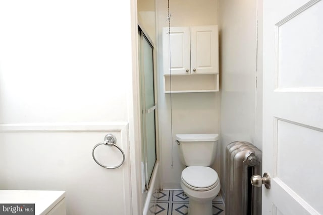 full bathroom featuring bath / shower combo with glass door, vanity, toilet, and radiator heating unit